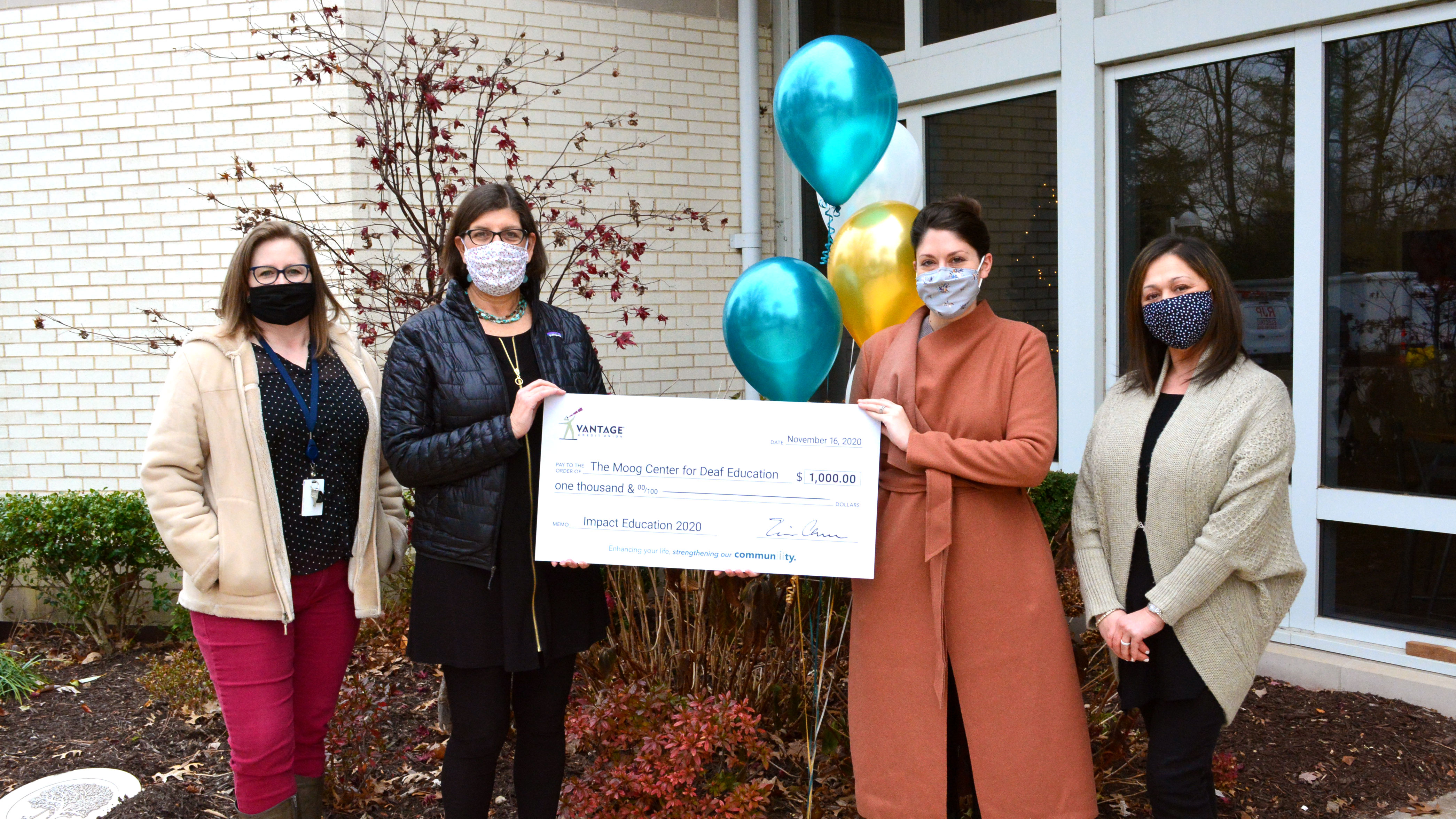 Four teachers holding a large check