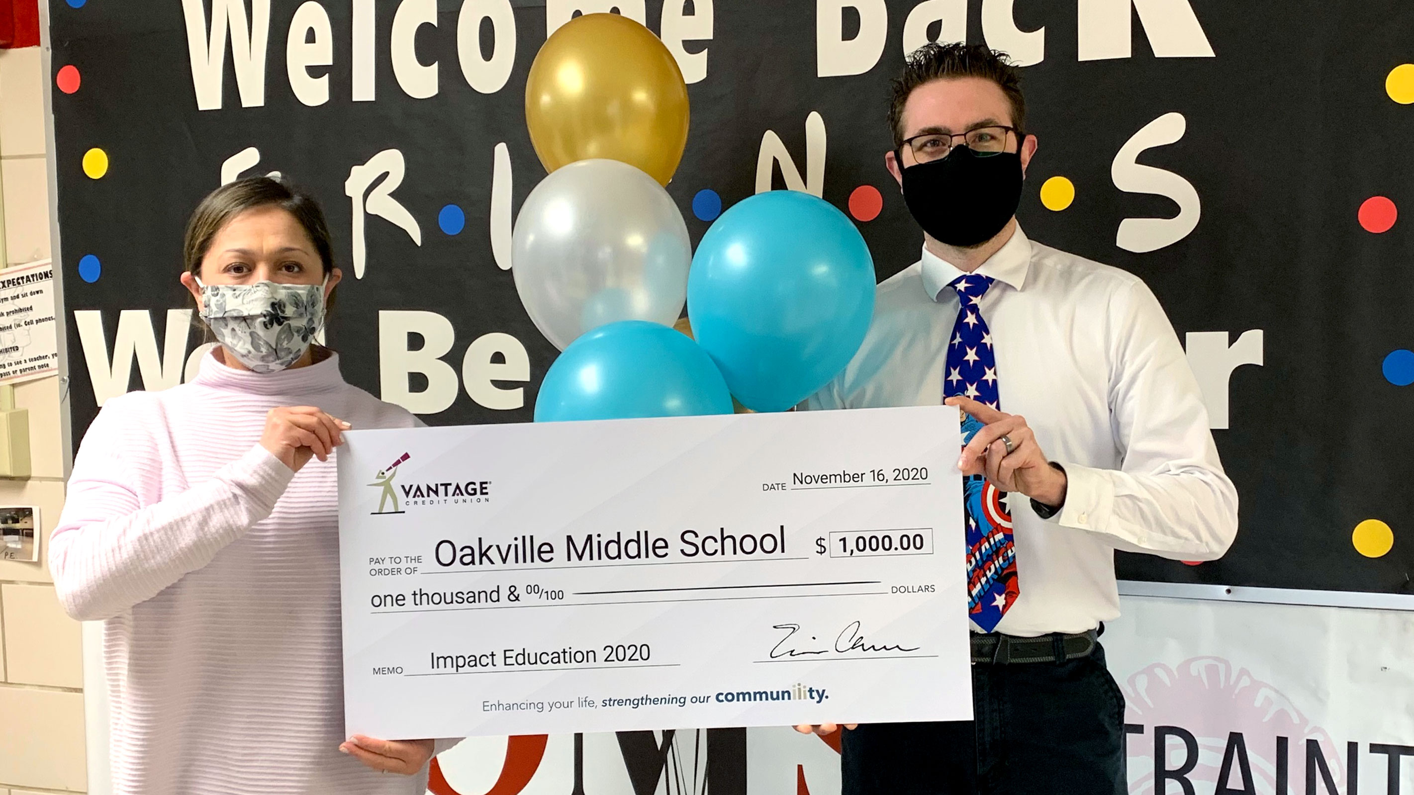 Two teachers holding a large check