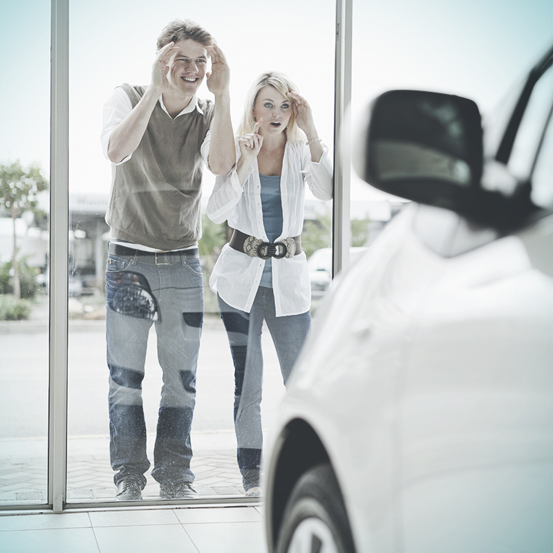 A couple looking through a window of a dealership
