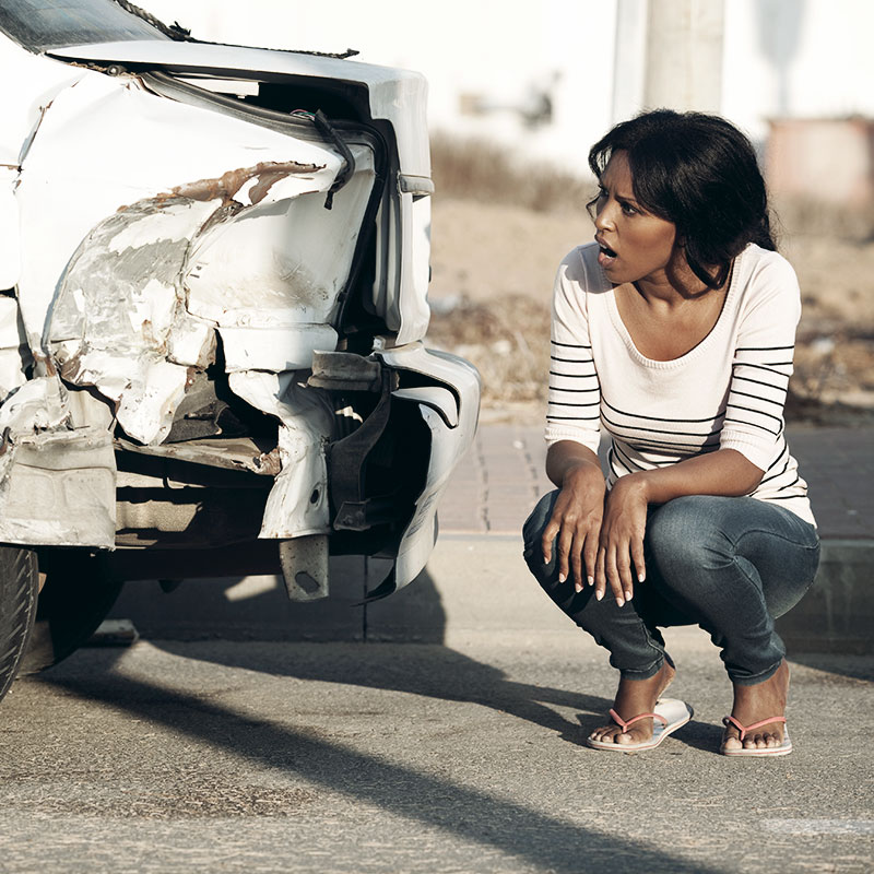 A woman looking at her car after an accident