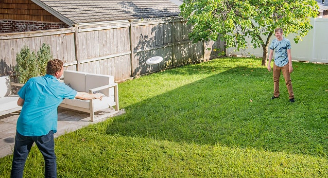 A father and son playing frisbee in their backyard