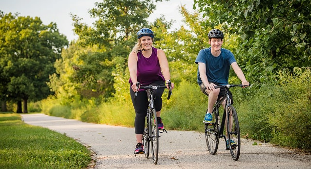Two people riding bikes down a path