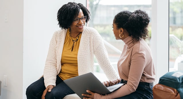 Two women having a conversation with a laptop